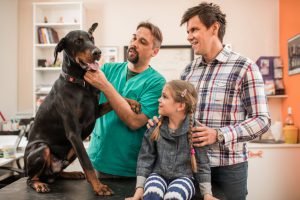 Happy father and daughter brought their dog at vet's office.